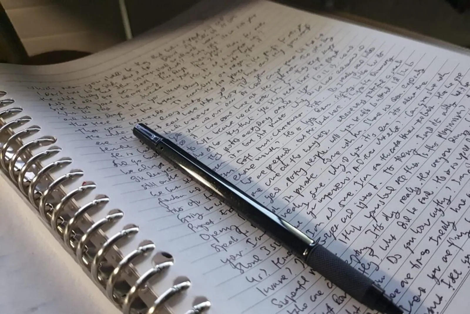 A handwritten page with a fountain pen resting across it